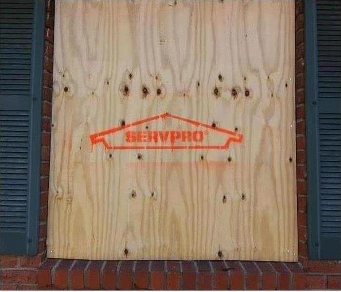 a boarded up building with light plywood with a SERVPRO logo on it