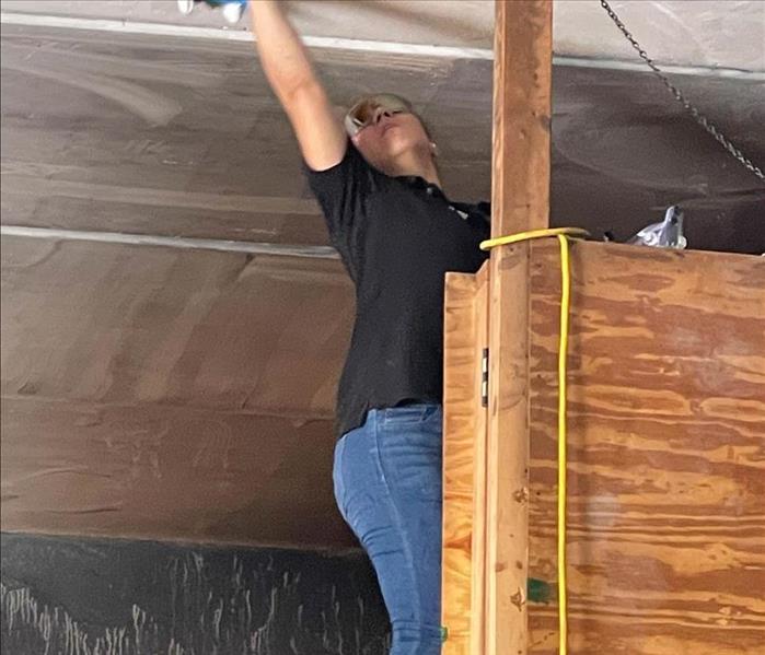 Employee cleaning soot from a ceiling.